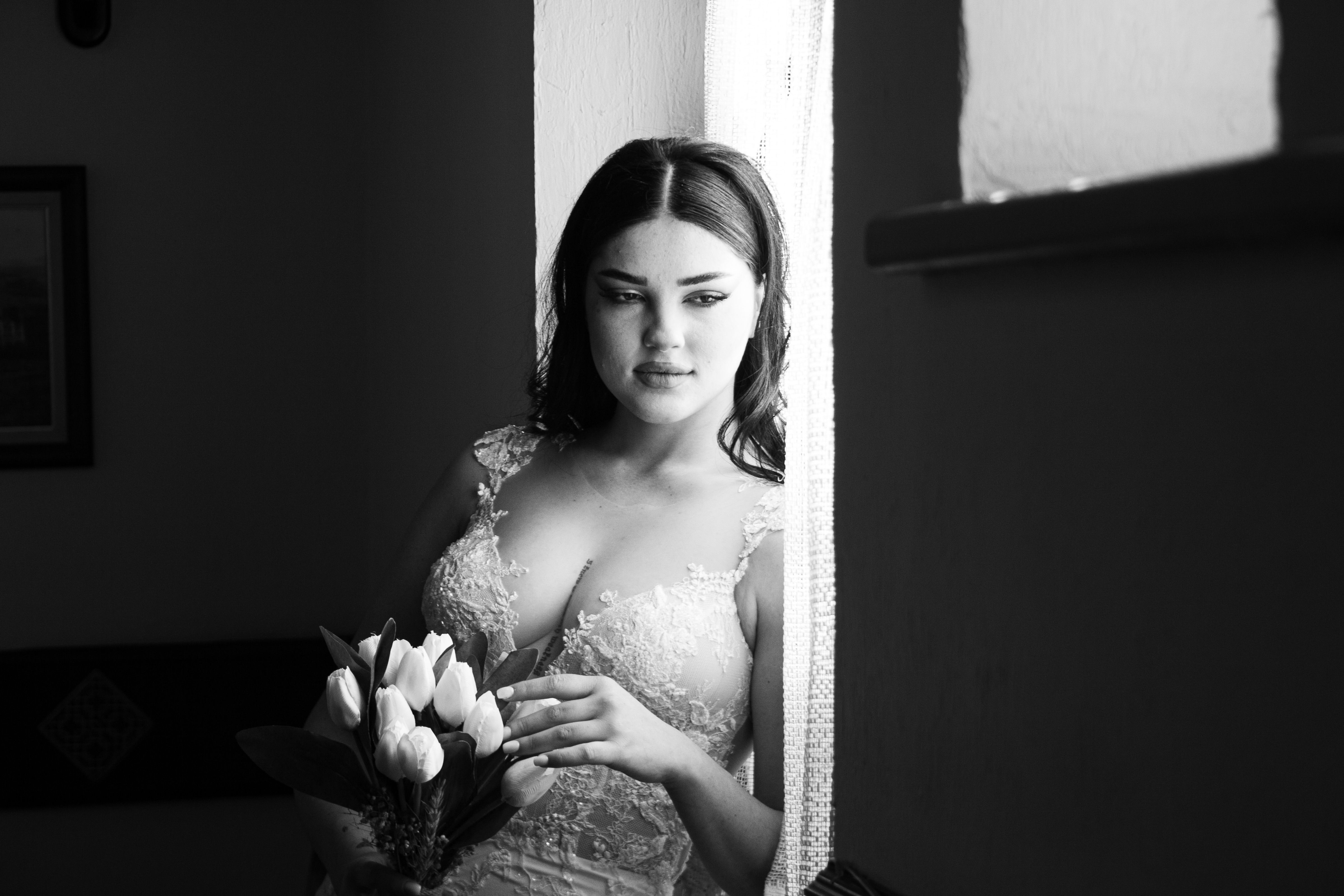 A stunning bride in a lace dress holding tulips, captured in black and white.