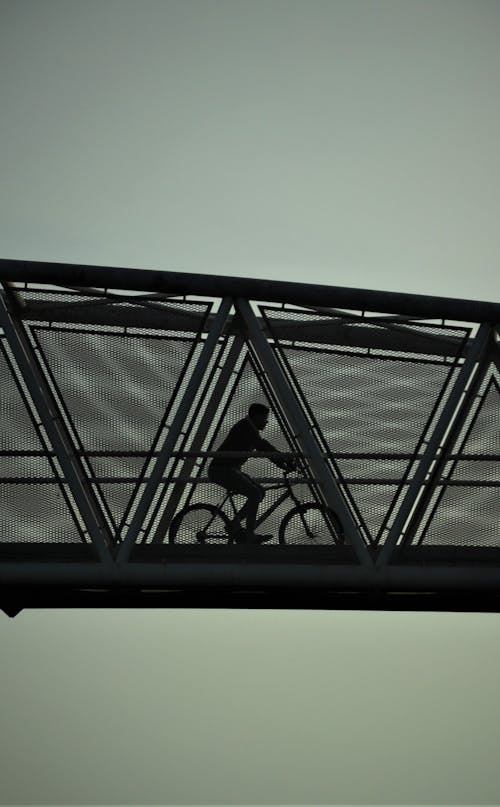 Man Riding a Bike on an Iron Bridge 