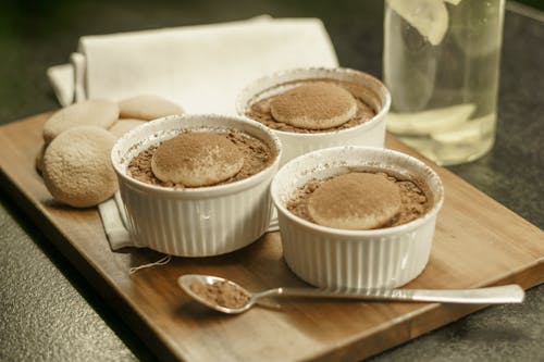 Three small bowls of chocolate pudding on a wooden tray