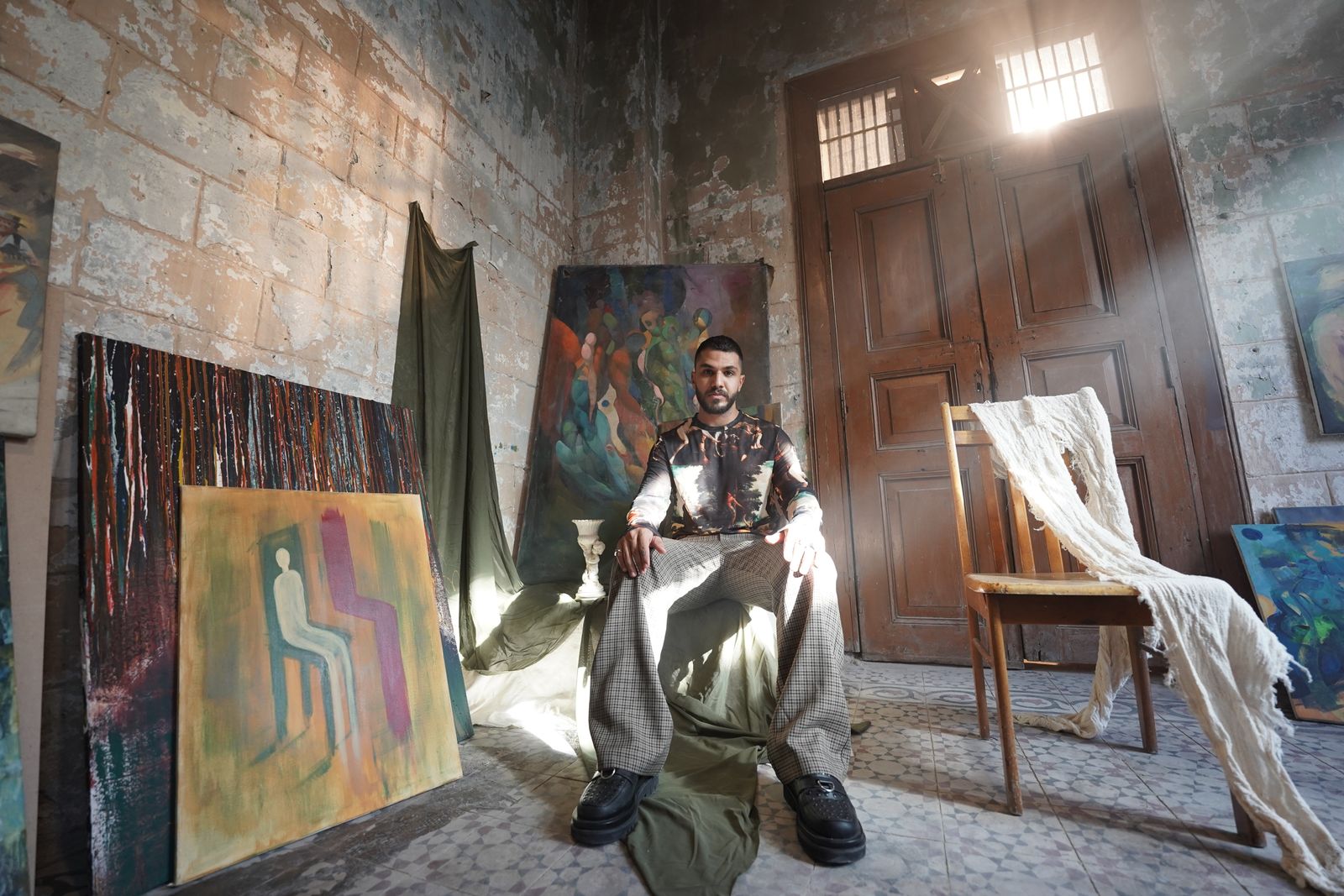 Collector seated among canvases in an atmospheric studio — photo by zaid mohammed on Pexels