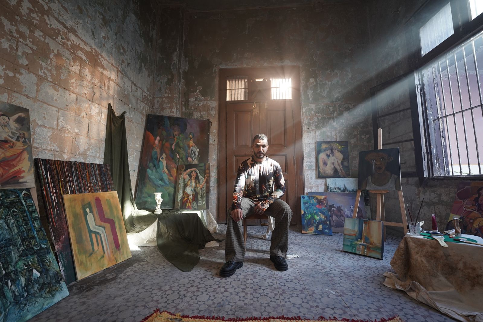Amari Voss seated in his studio, surrounded by canvases — photo by zaid mohammed on Pexels