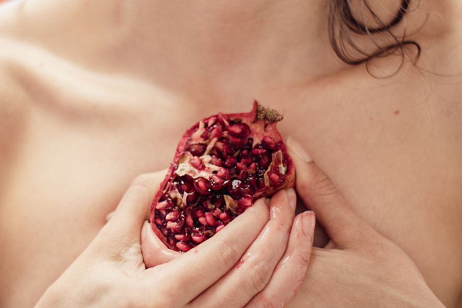 An intimate close-up of a woman's hands holding a juicy pomegranate, showcasing texture and color.
