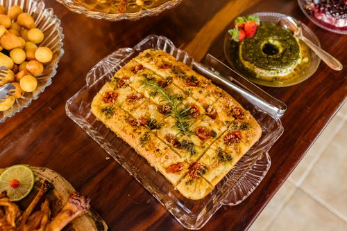 Free Delicious homemade tomato focaccia bread displayed with various appetizers on a rustic wooden table. Stock Photo