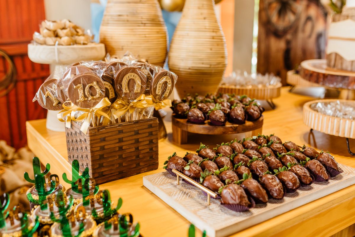 Elegant display of chocolate desserts featuring covered strawberries and lollipops on a buffet table.