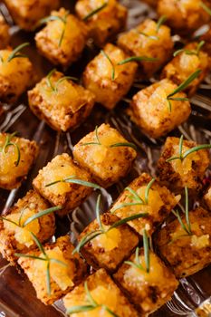 Golden brown tofu cubes garnished with rosemary, perfect for vegan party appetizers.