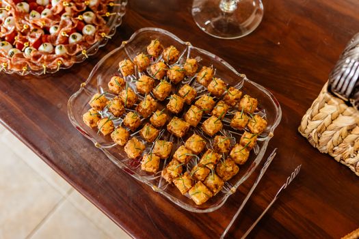 Crispy tofu appetizers served on a tray atop a wooden table, perfect for parties.