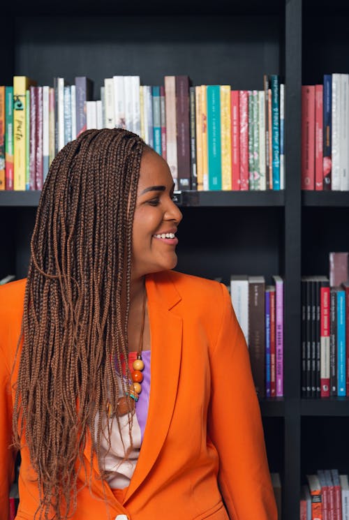 Smiling Woman with Braided Hair Standing in front of a Bookshelf