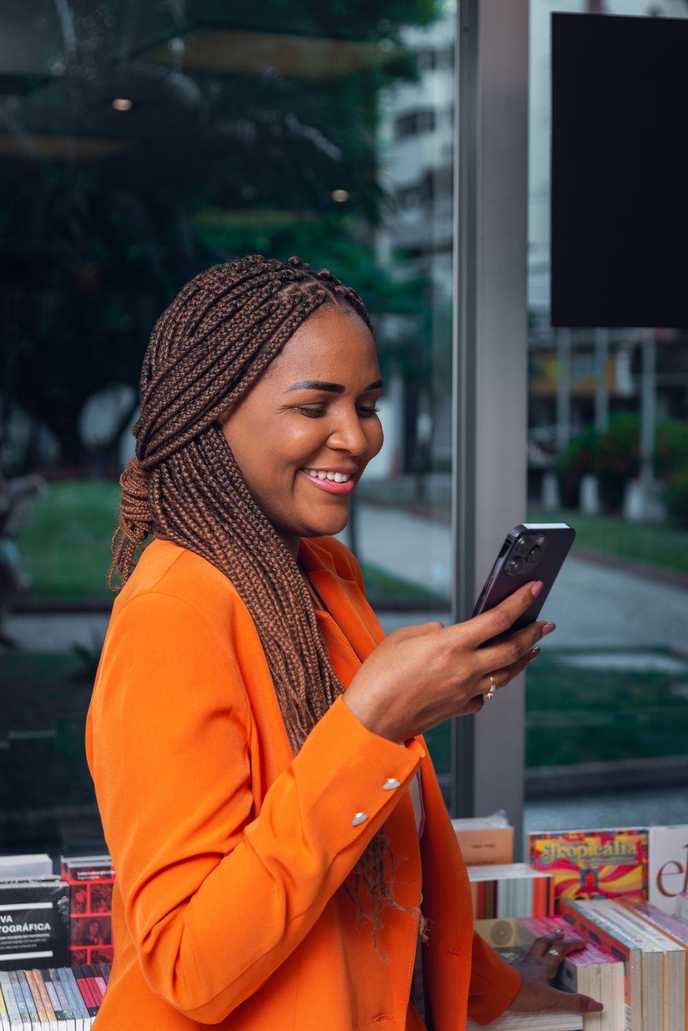 Business owner in an orange blazer checking her group on her phone