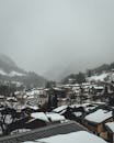 白雪皑皑的村庄坐落在阿尔卑斯山上，雾蒙蒙的山脉为背景，构成一幅迷人的冬日景象