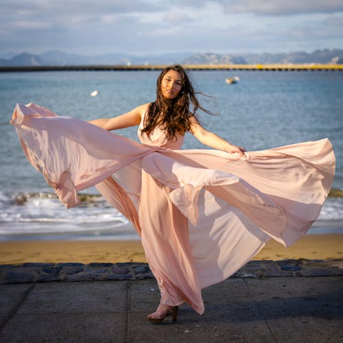 Woman Wearing Pink Dress Posing by the Shore