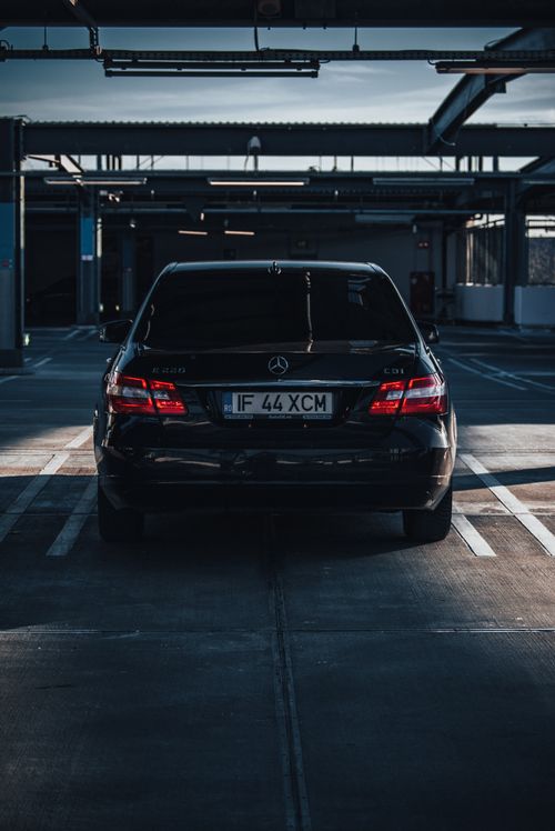 Free Black Mercedes-Benz car parked in a dimly lit parking garage highlighting urban automotive design. Stock Photo