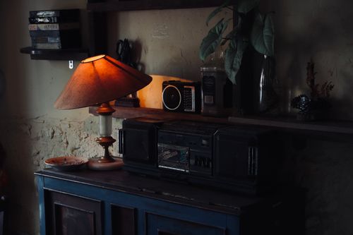Free Cozy vintage interior with a warm lamp illuminating a wooden cabinet and retro radio. Stock Photo