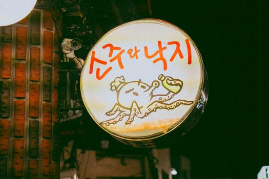 A vibrant signage of a Korean restaurant featuring an octopus illustration against a dark backdrop.