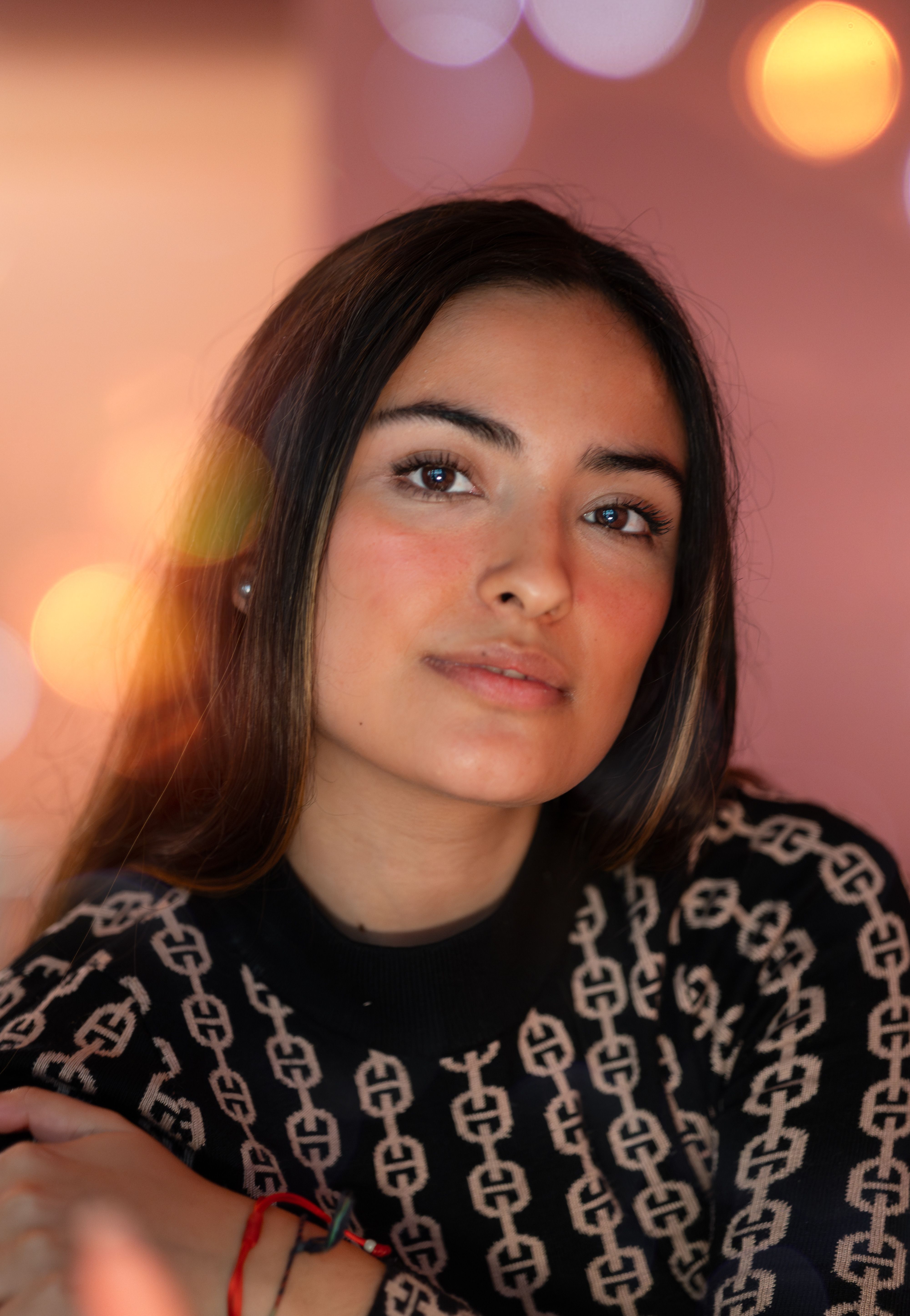 Elegant portrait of a woman in patterned knitwear with bokeh lights background, conveying warmth and style.