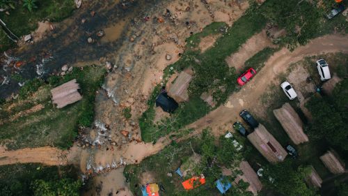 Free A stunning aerial view showcasing a riverside campsite with tents and vehicles, surrounded by nature. Stock Photo