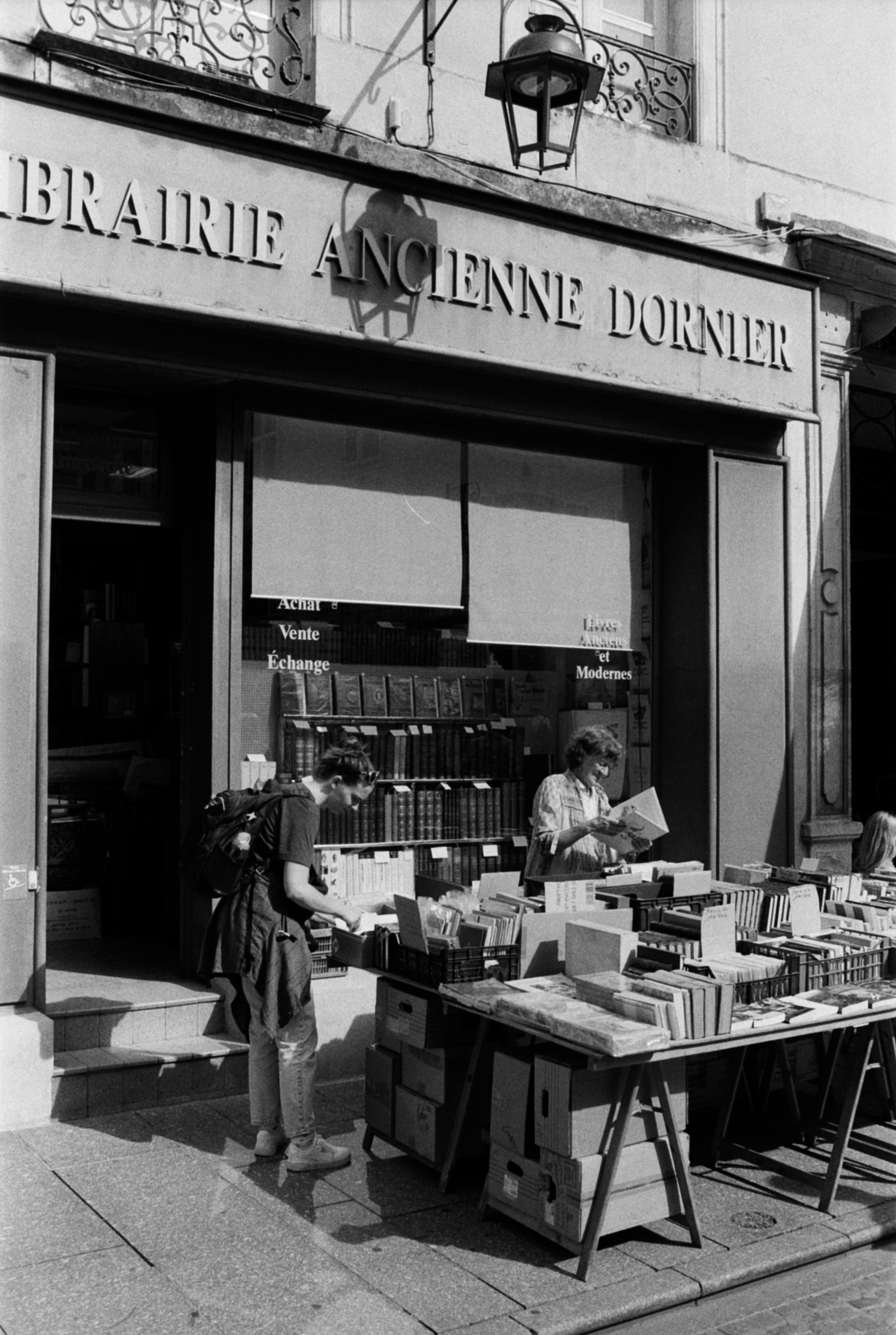 A charming outdoor bookstore display in Nancy, France, with vintage appeal and book enthusiasts browsing.
