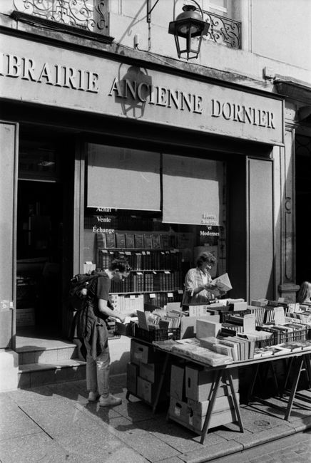 A charming outdoor bookstore display in Nancy, France, with vintage appeal and book enthusiasts browsing.
