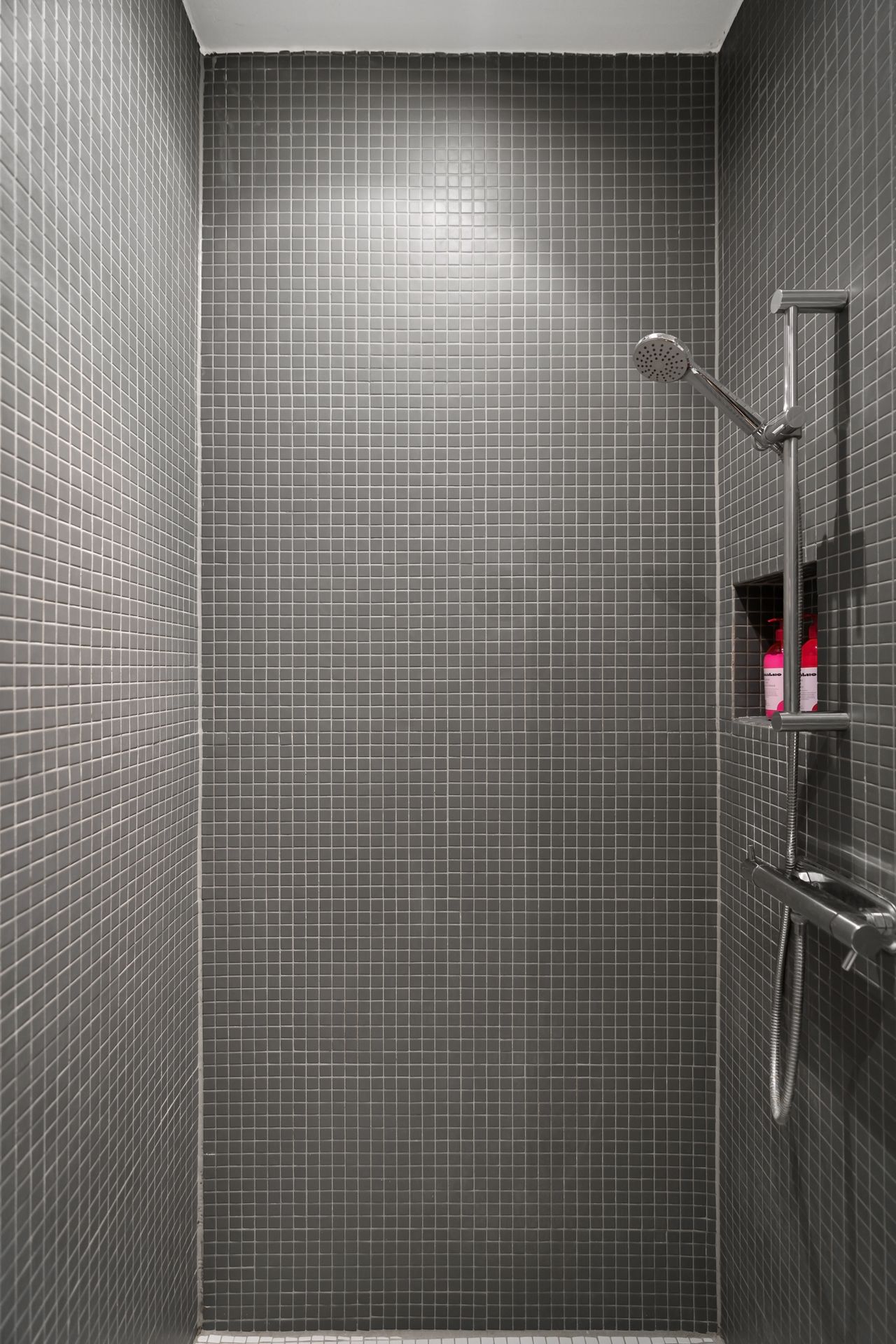 Fully open gray mosaic walk-in shower with no glass panels and a wall niche