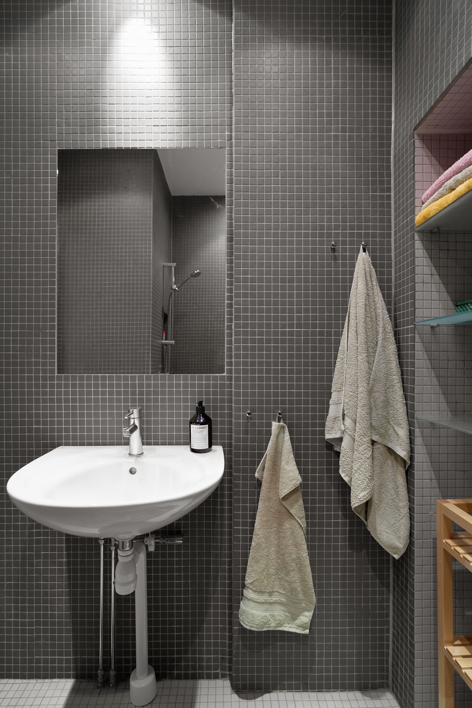 Compact minimalist bathroom with grey tiles, sink and mirror