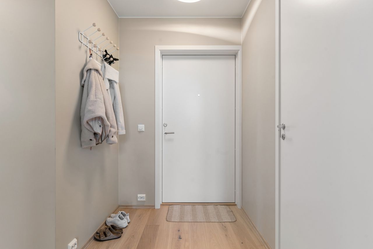 Small entryway with a white front door and wall-mounted coat hooks