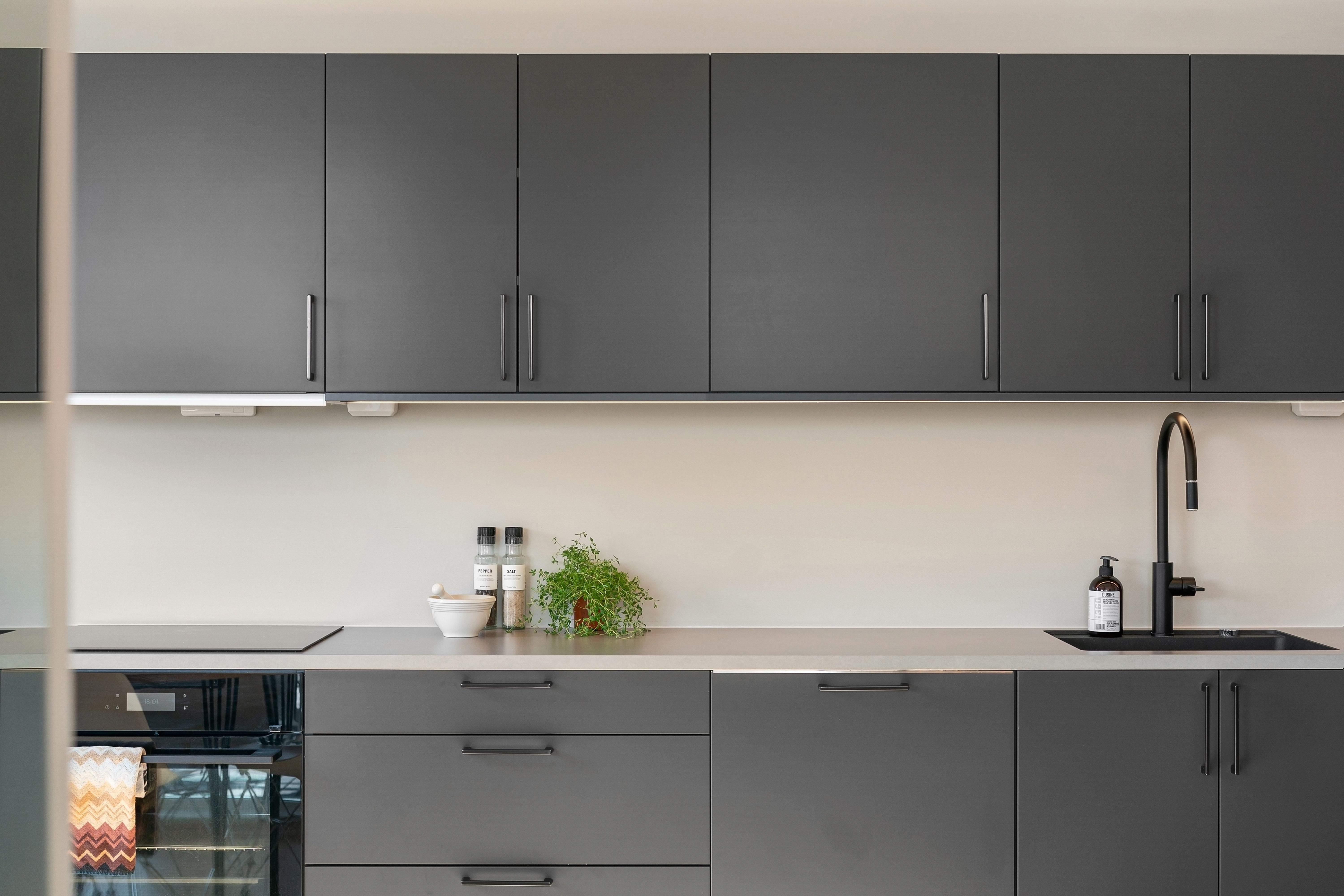 A modern kitchen with grey cabinets and black appliances · Free Stock Photo