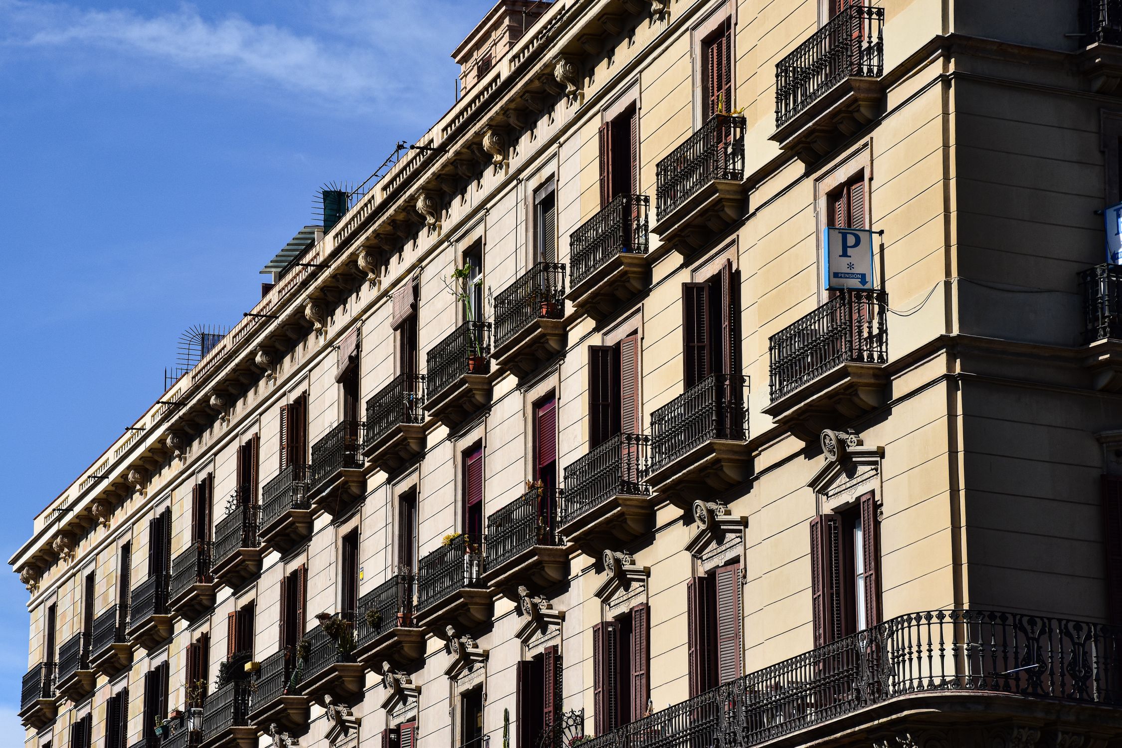 Side view of a beautiful Barcelona building facade with ornate balconies under a clear blue sky