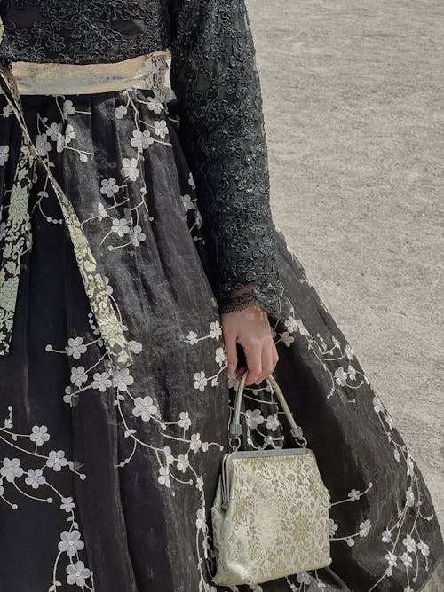 Close-up of Woman in a Dress with Embroidered Flowers Holding a Purse 