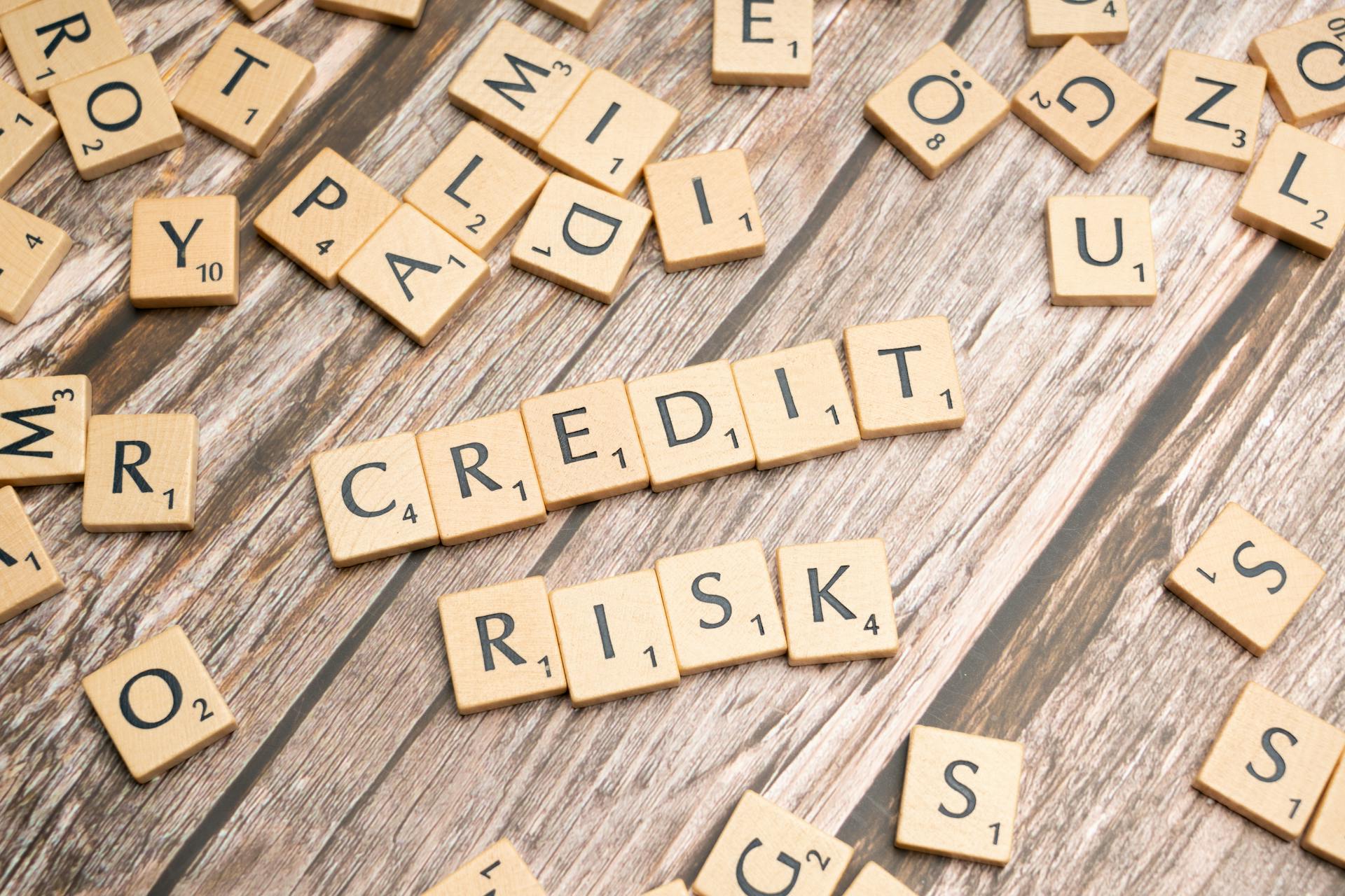 Scattered wooden letter tiles spelling 'credit risk' on a rustic wooden surface.