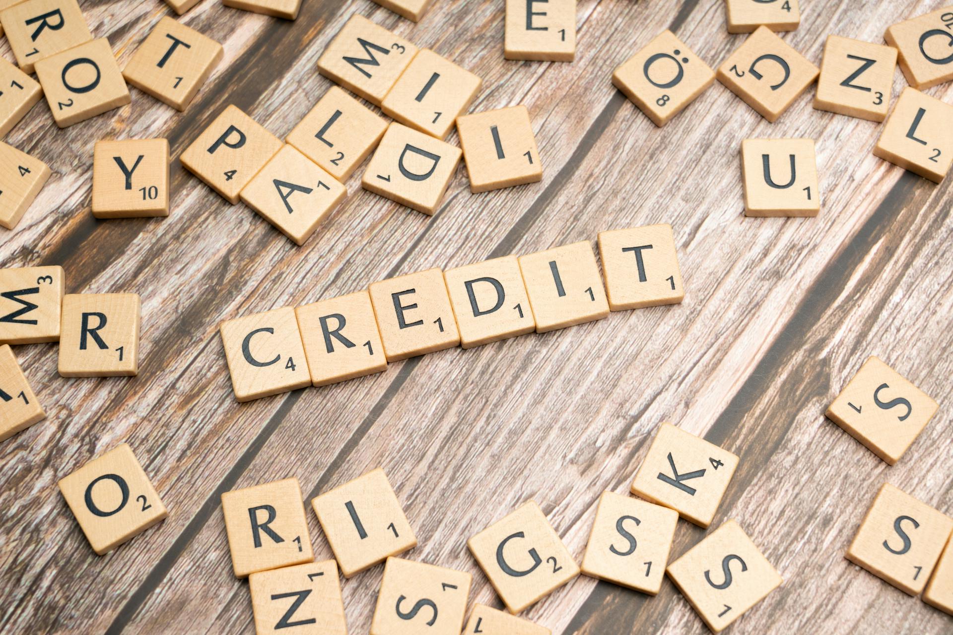 Wooden letter tiles arranged to spell 'CREDIT' on a rustic table background.