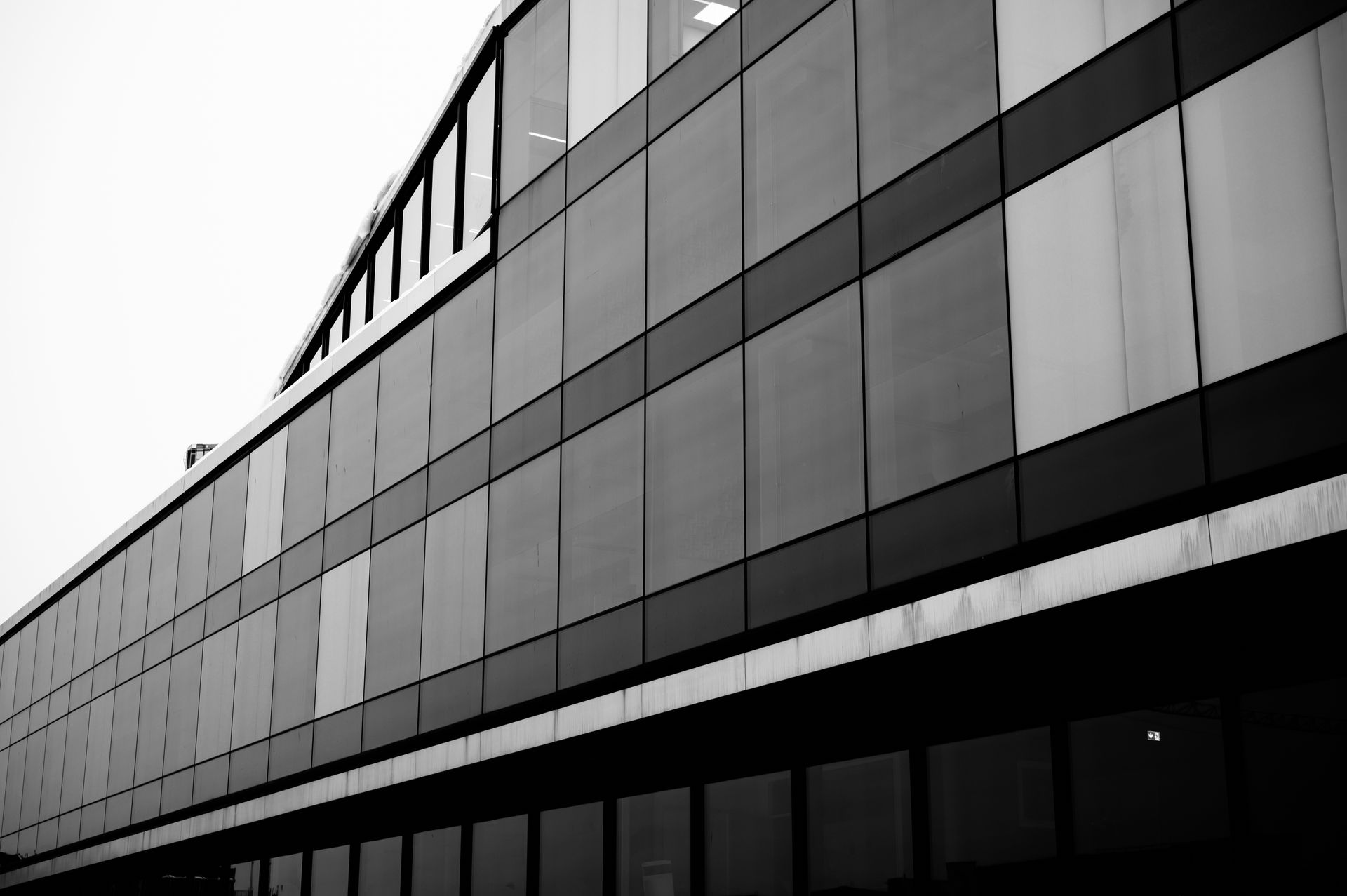 Black and white photo of a modern glass building in Oslo, showcasing sleek architectural lines.
