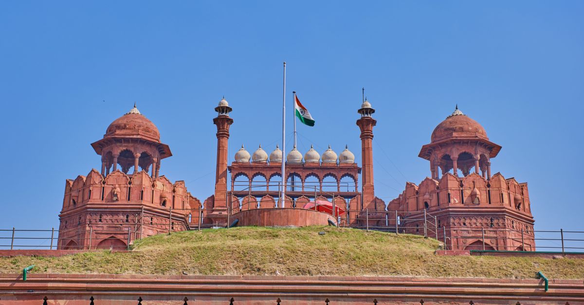 The historic Red Fort in Delhi with the Indian national flag flying under a clear sky.