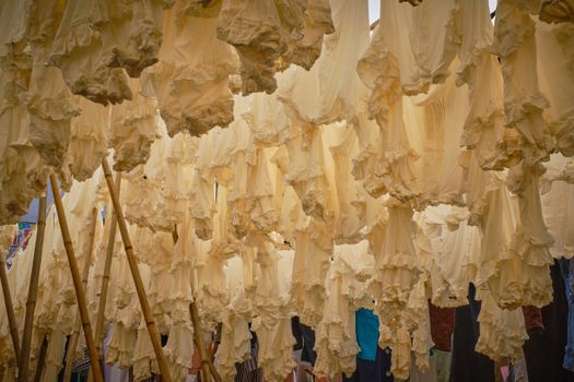 White garments hanging outdoors on bamboo poles, creating a textured pattern of clothing.