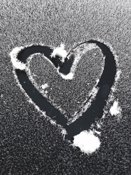 Free Black and white photo of a heart shape drawn on a frosted window, evoking winter romance. Stock Photo
