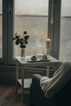 A serene indoor scene with candlelight and flowers by the window.