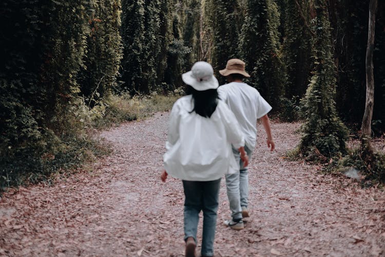 Two People Walking In Hats In A Park