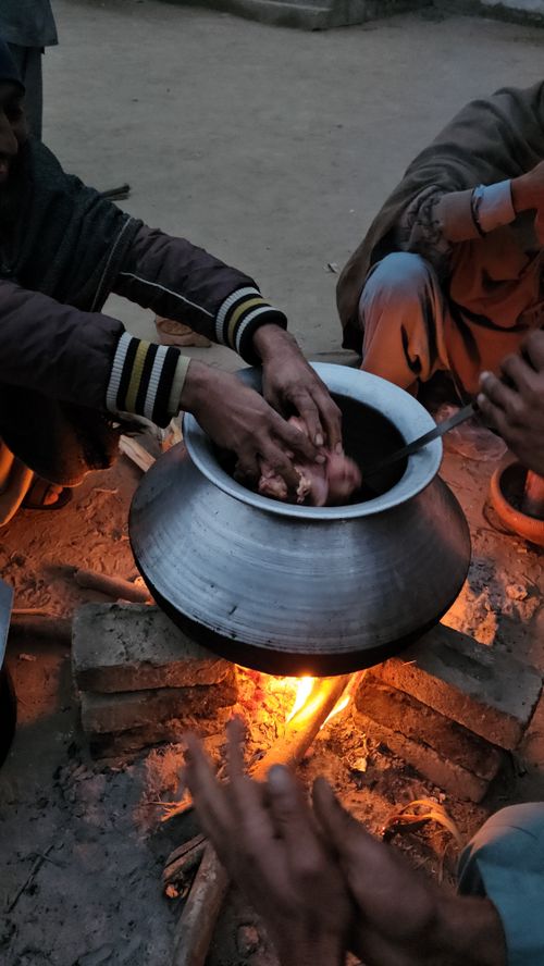 Free Hands cooking over a bonfire in a rural setting during twilight, showcasing traditional culinary practices. Stock Photo
