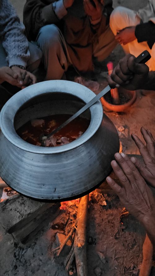 Free A group of people cooking stew outdoors over a bonfire in a rustic setting. Stock Photo