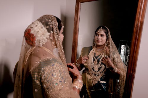 Bride in Traditional Dress Standing by Mirror