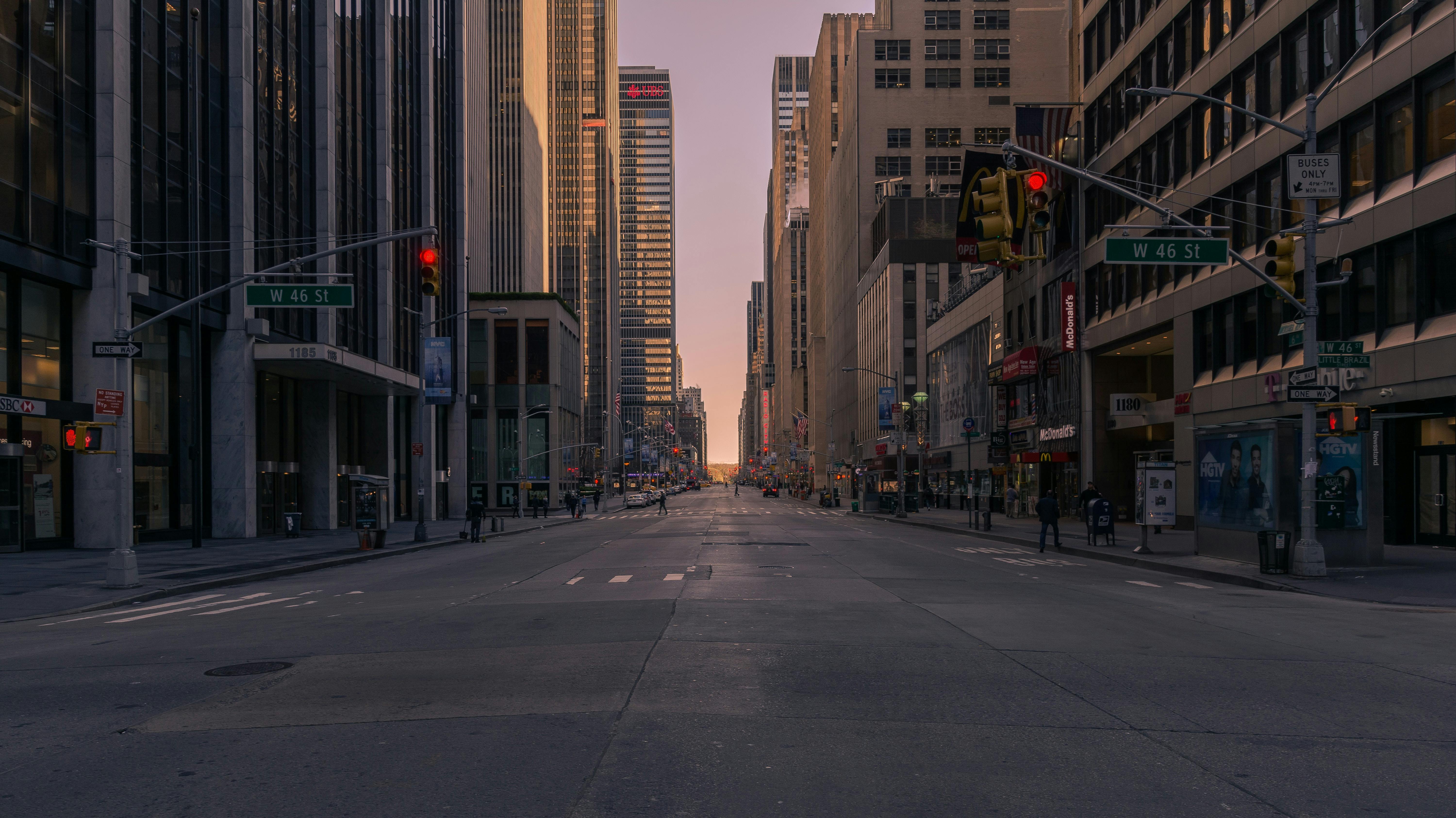 Empty New York City street at sunset with towering skyscrapers and soft glowing light.