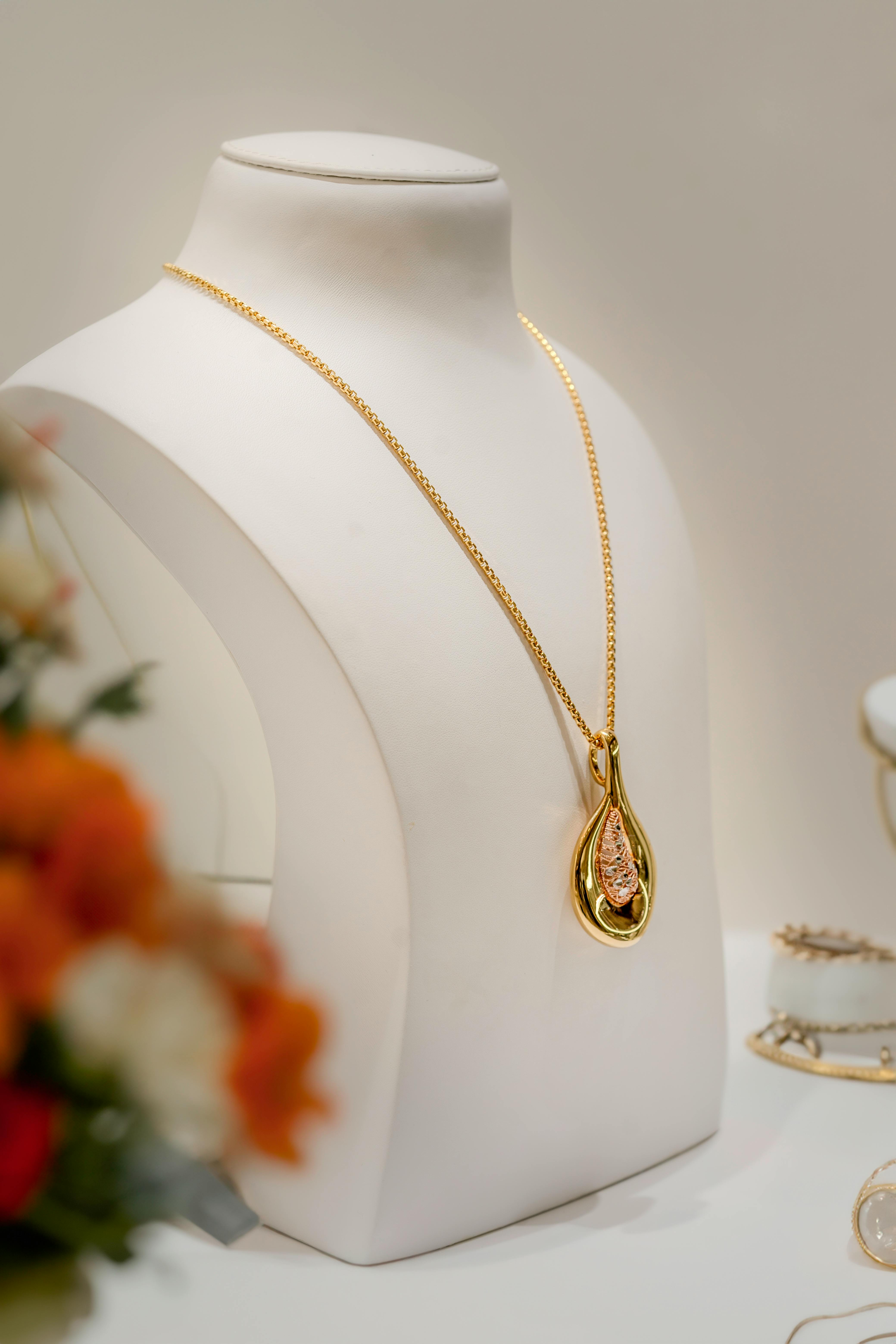 Handcrafted gold necklace with ornate pendant displayed on jewelry stand