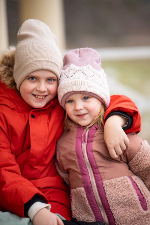 Free Adorable siblings in warm jackets and hats smiling and hugging, captured in a winter outdoor setting. Stock Photo