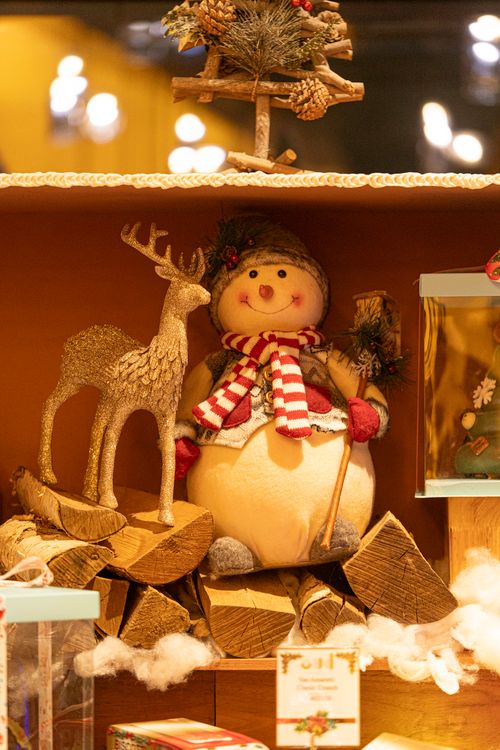 Free Charming Christmas scene with snowman and reindeer decoration on wooden logs. Stock Photo