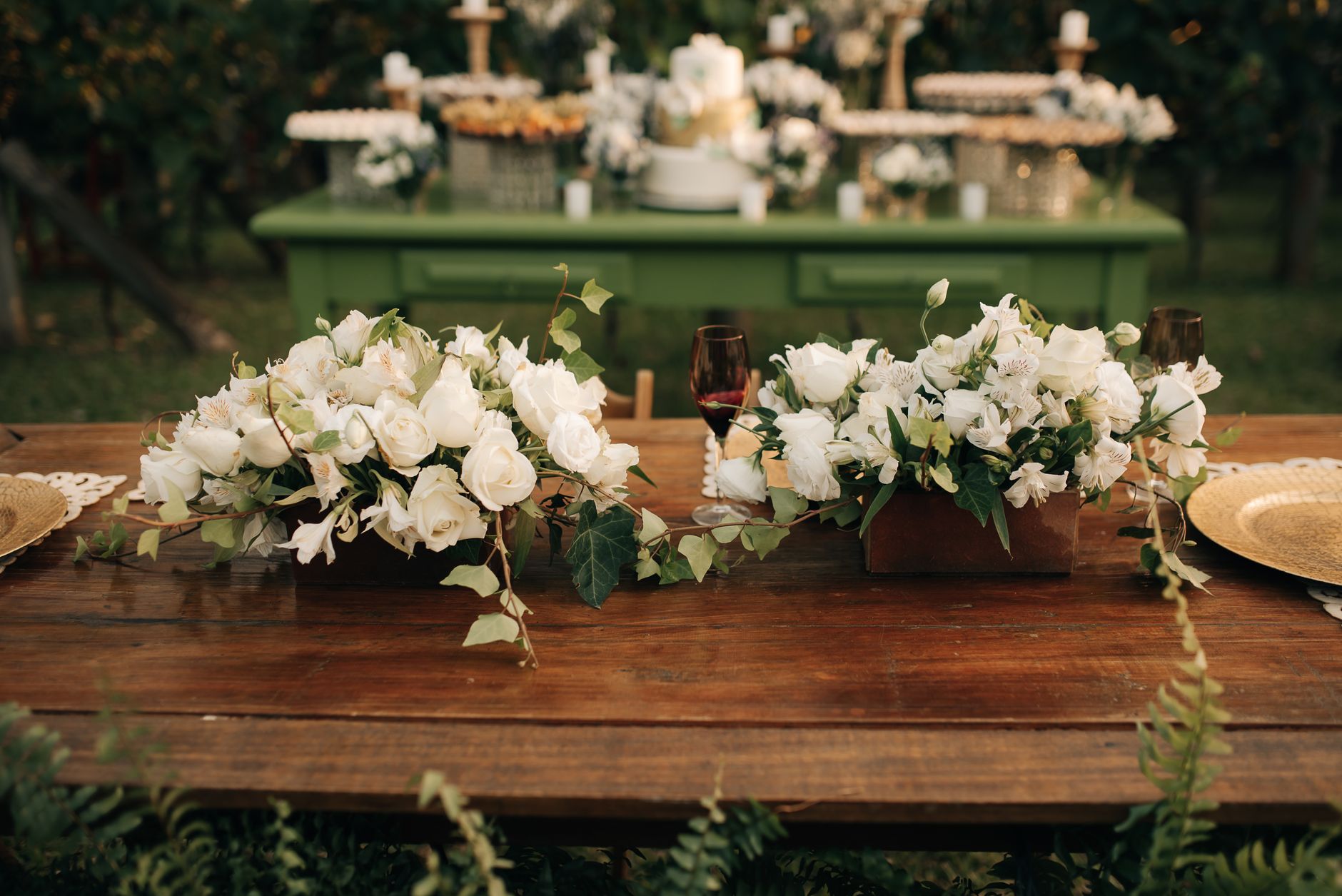 Rustic wooden table adorned with white floral arrangements for an outdoor wedding.