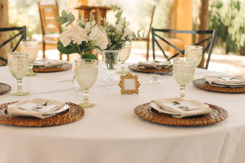 Free Chic outdoor wedding table setup with floral centerpiece and elegant tableware on a sunny day. Stock Photo