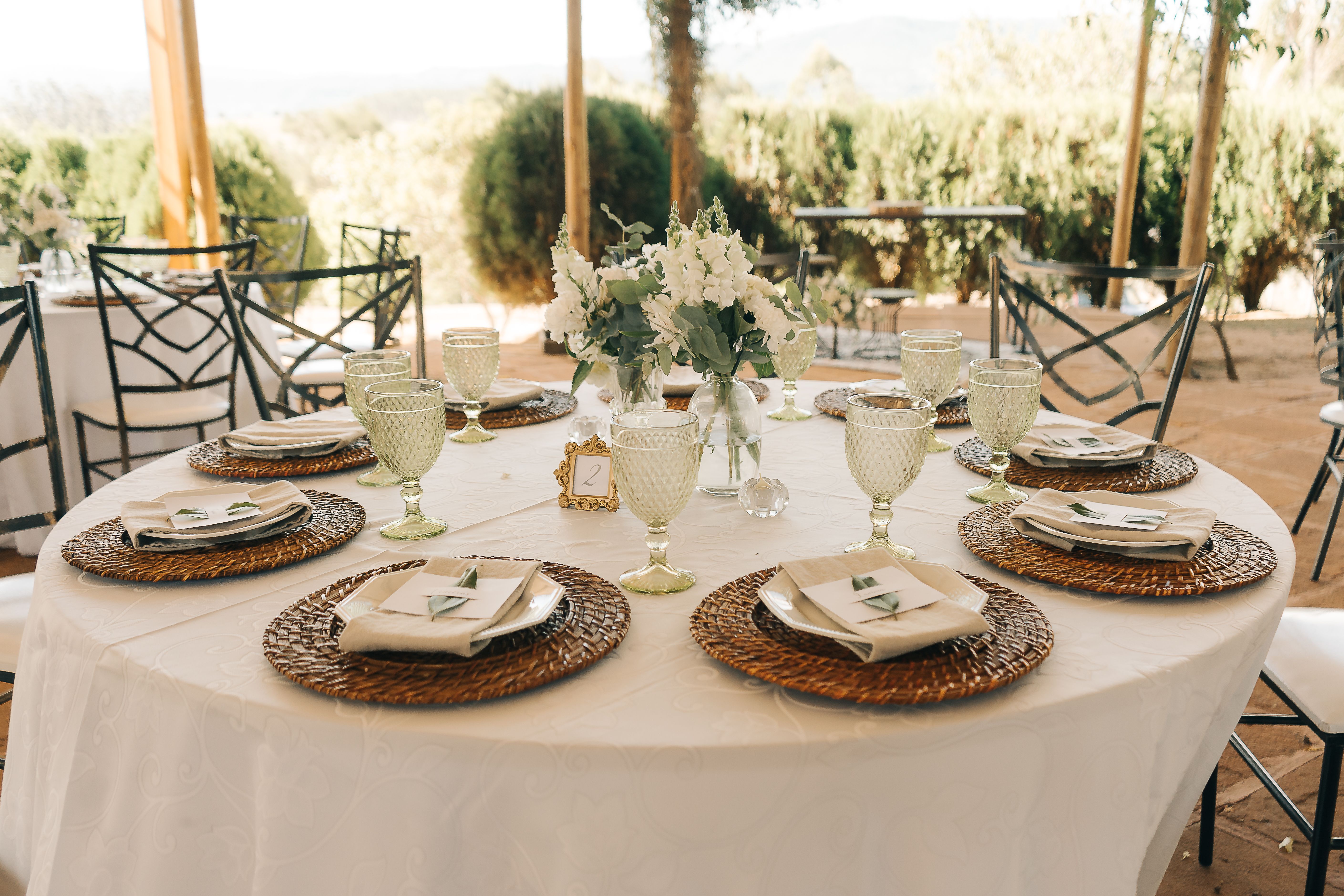 A beautifully arranged outdoor wedding table with elegant glassware and floral centerpiece, perfect for a summer event.