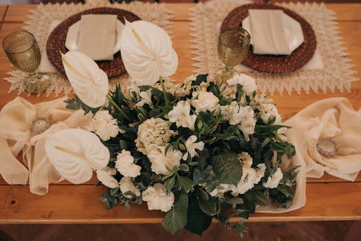 Romantic wedding table setting featuring a white floral centerpiece and elegant tableware.