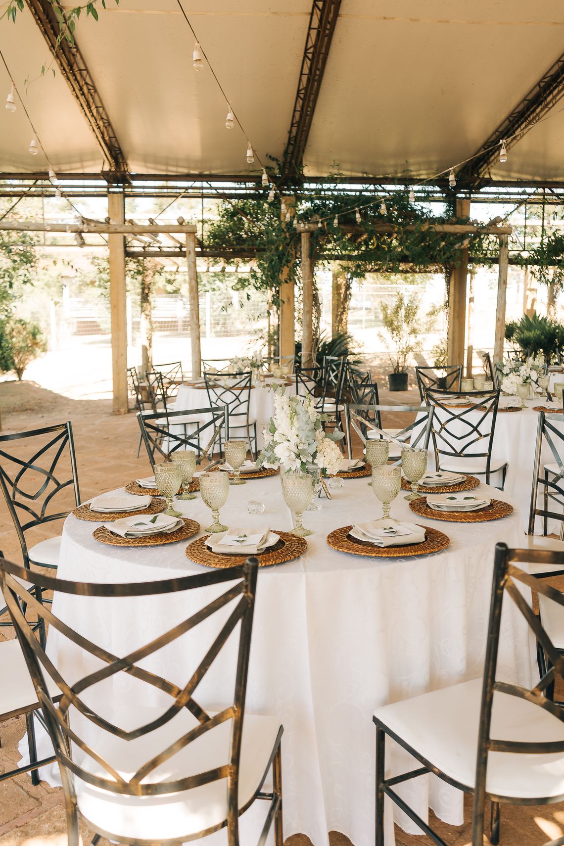 Outdoor wedding reception tables arranged with flowers, tableware, and elegant event decor