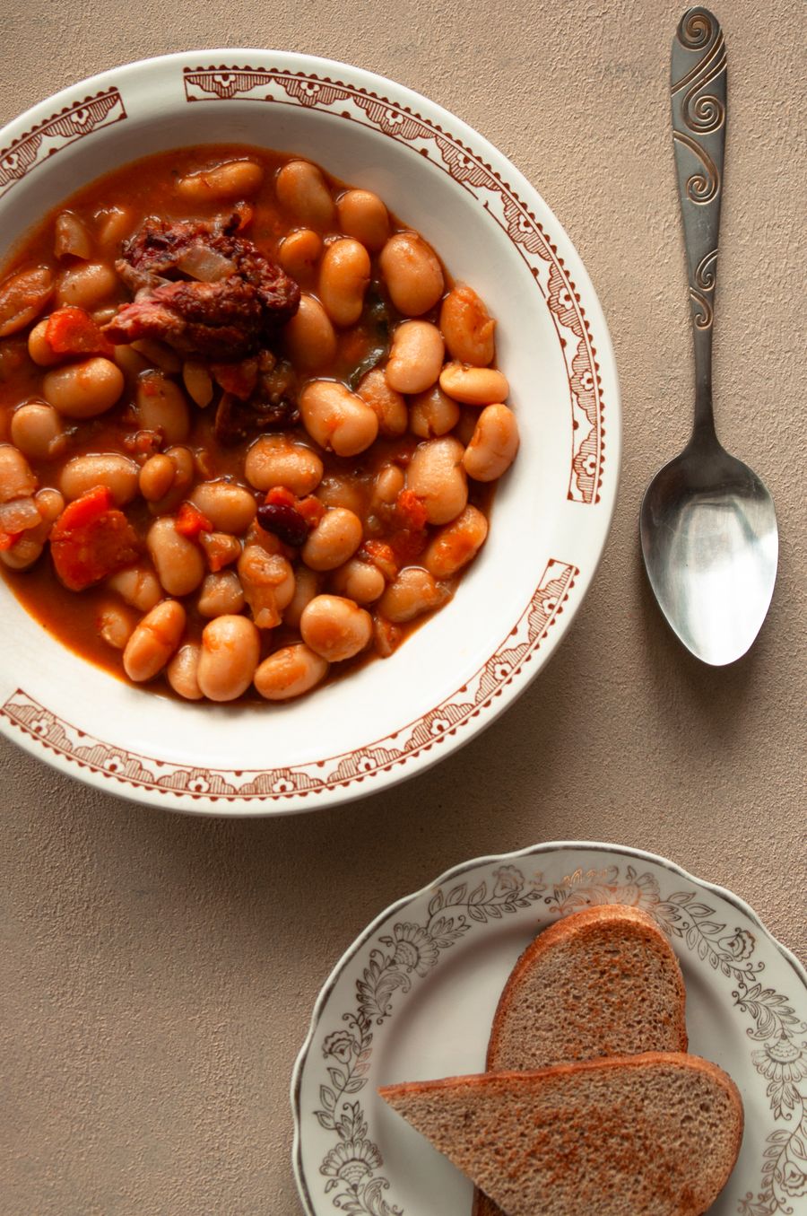 A rustic bowl of white beans with sausage and meat