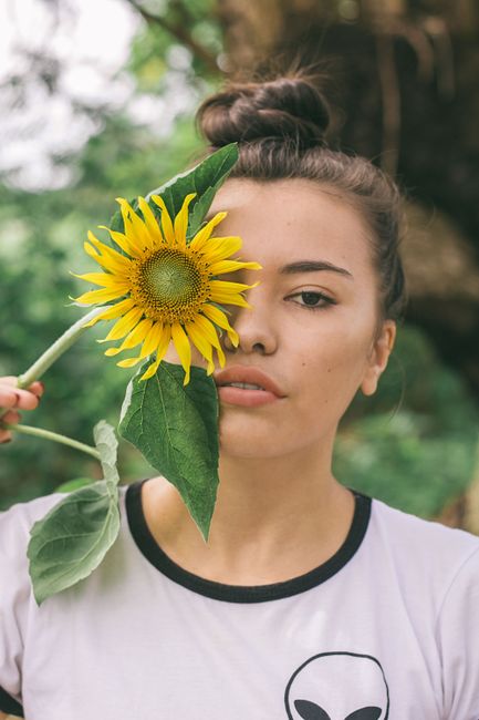 Young woman with sunflower in an outdoor setting, capturing natural beauty and style.