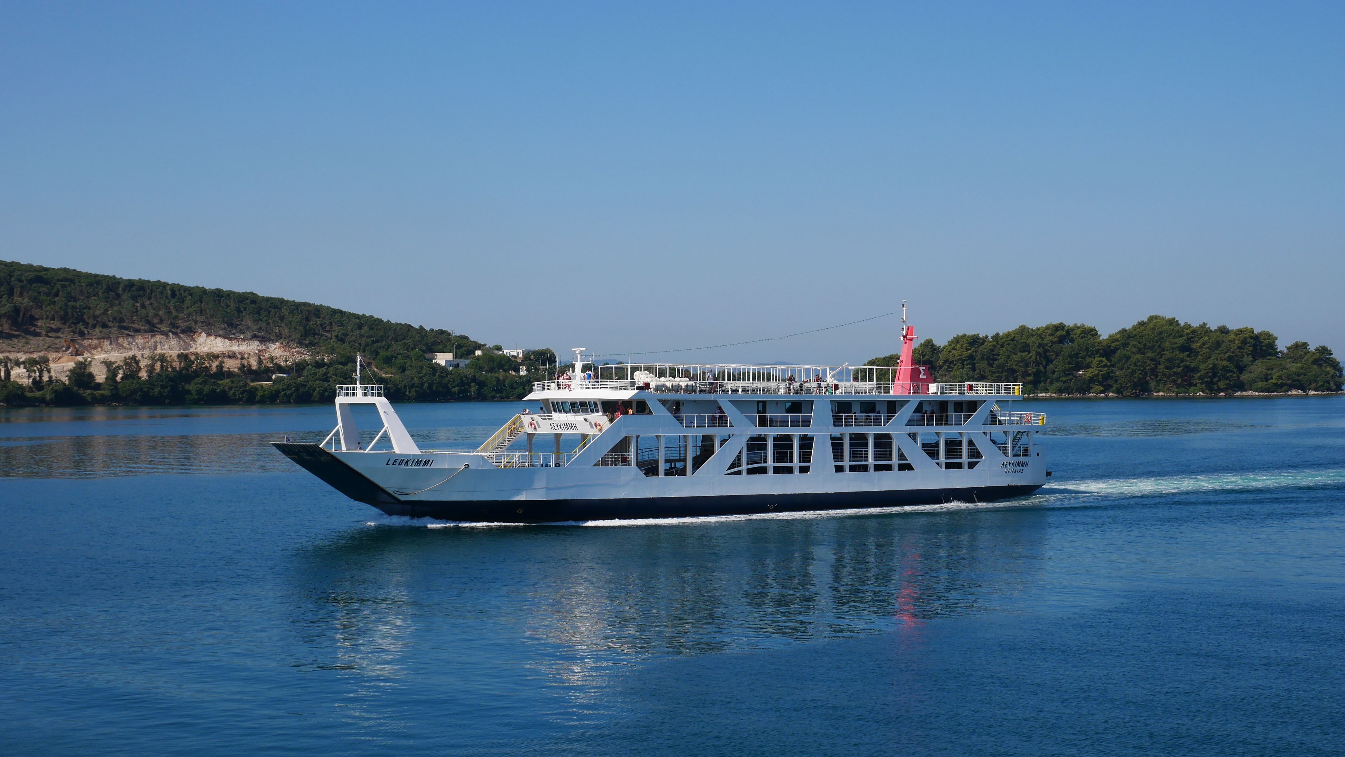 A cruise ship sails through the calm seas of Corfu, Greece, under a clear summer sky.